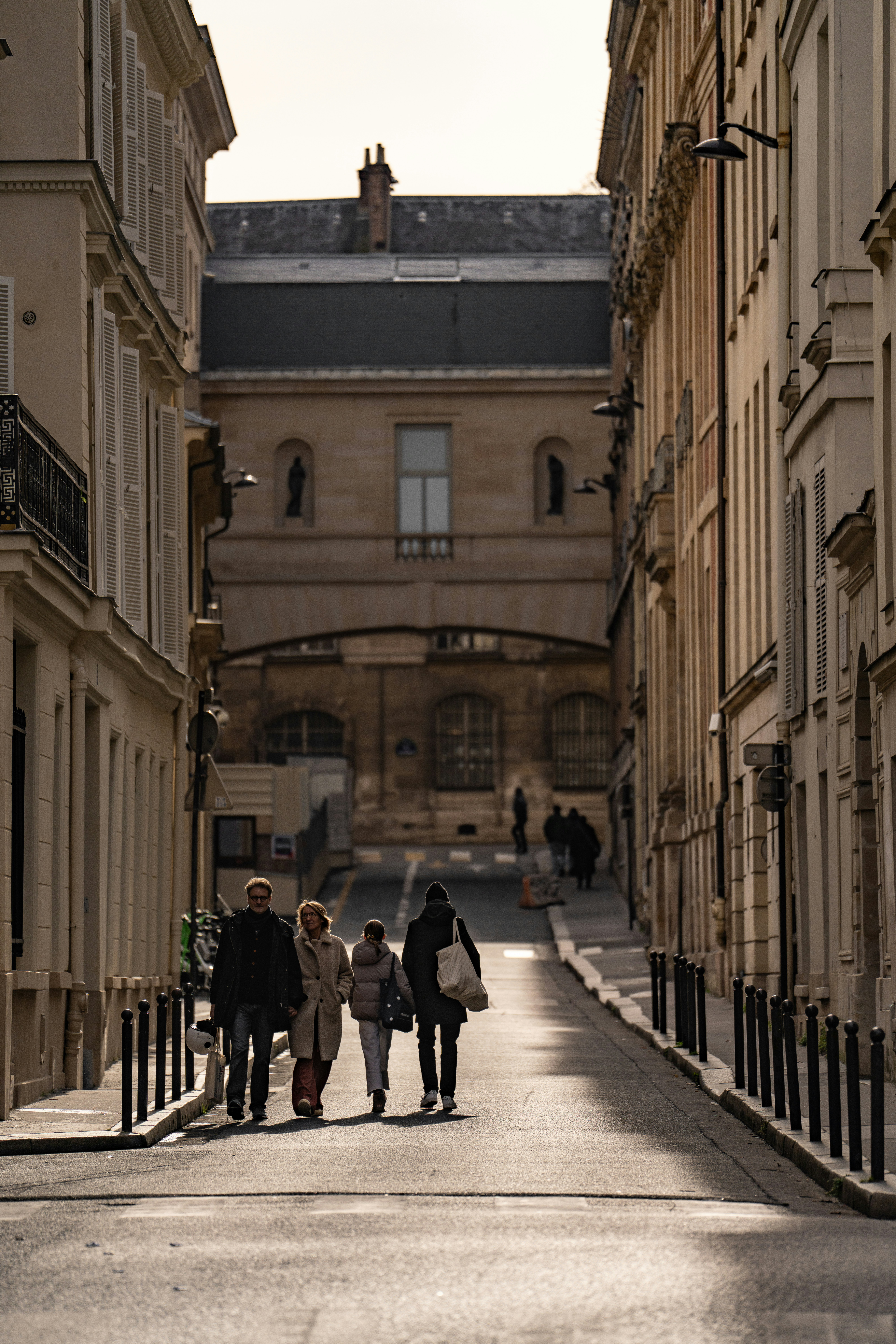 A group of people walking down a street next to tall buildings