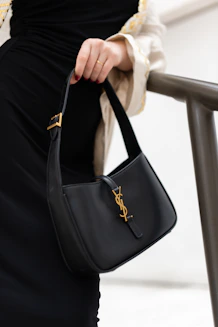 A woman in a black dress holding a black handbag