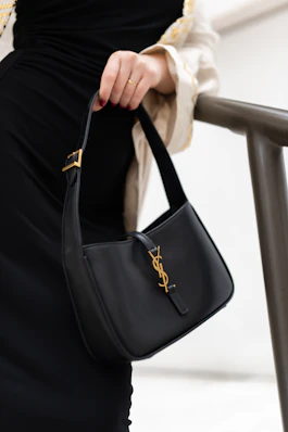 A woman in a black dress holding a black handbag