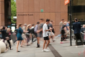 A crowd of people walking down a street next to a tall building
