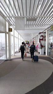 A group of people walking down a hallway with luggage