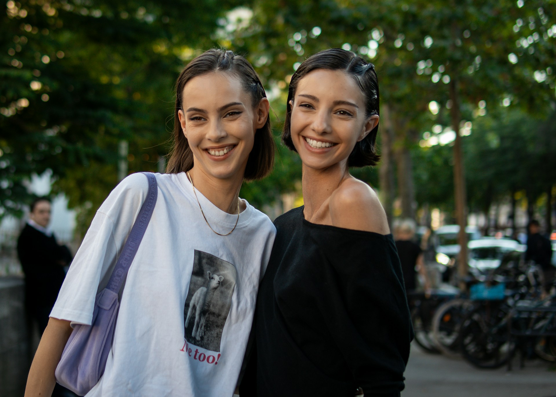 Two women standing next to each other on a sidewalk