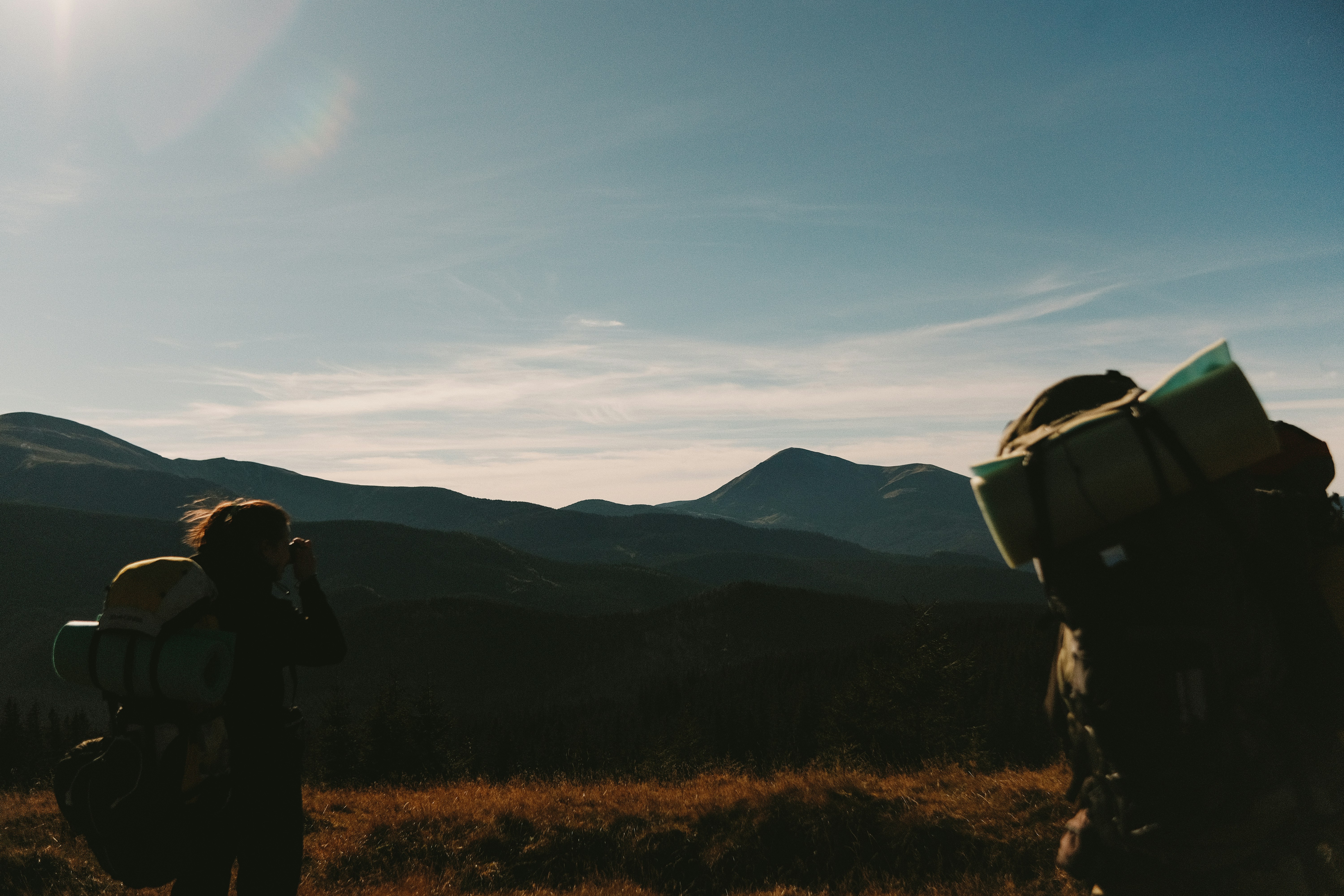 A couple of backpackers walking across a grass covered field