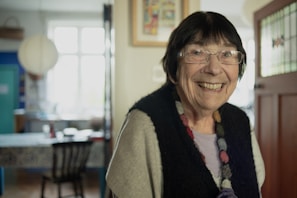 A woman with glasses smiling in a room