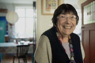 A woman with glasses smiling in a room