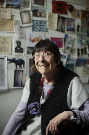 A woman sitting in a chair in front of a wall with pictures on it