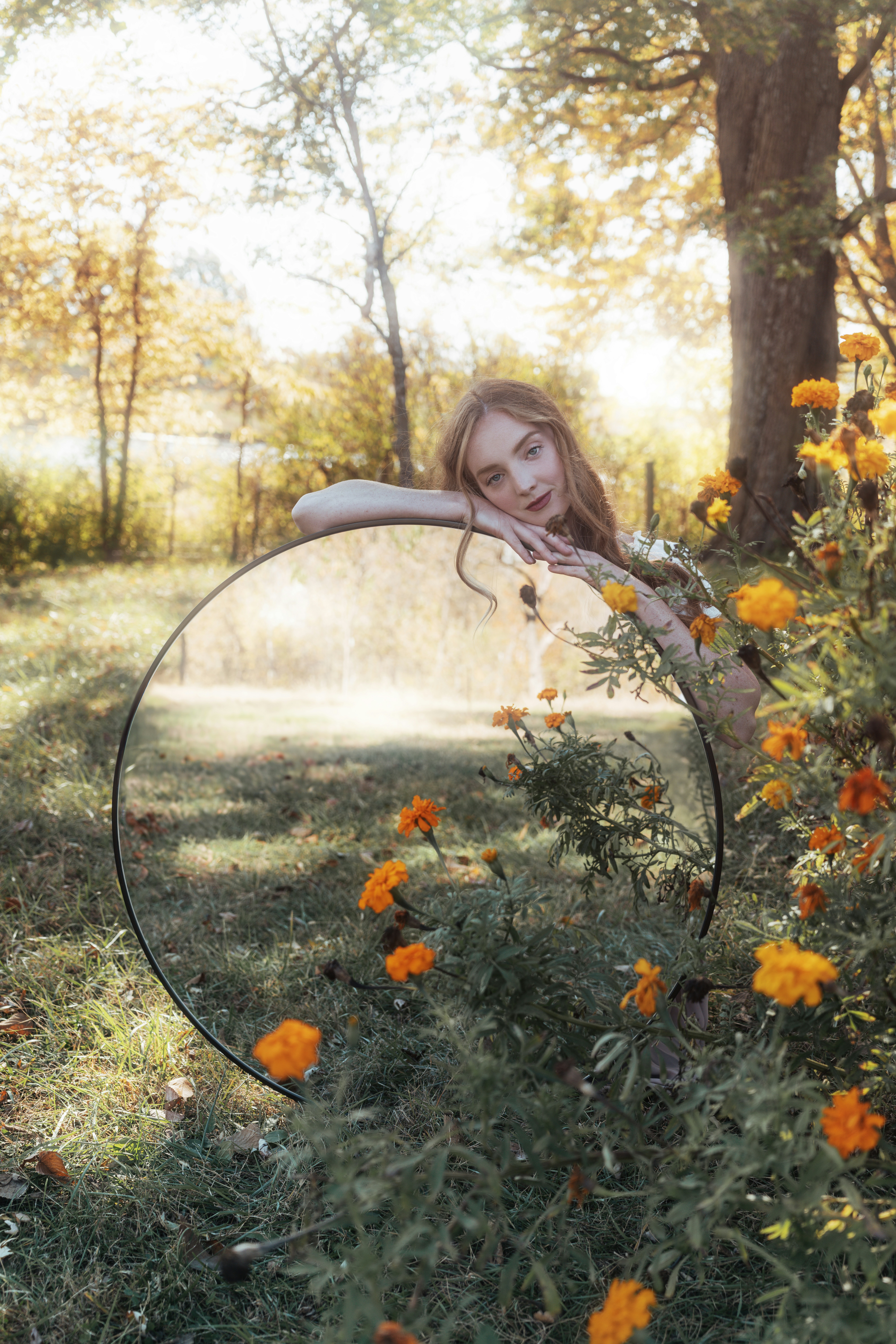 Una donna che tiene uno specchio in un campo di fiori