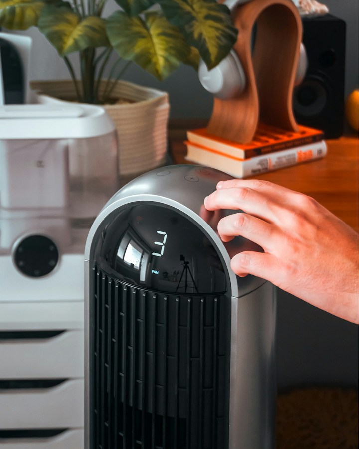 Adjusting fan speed on a modern electronic HEPA air purifier unit for wildfire smoke filtration.