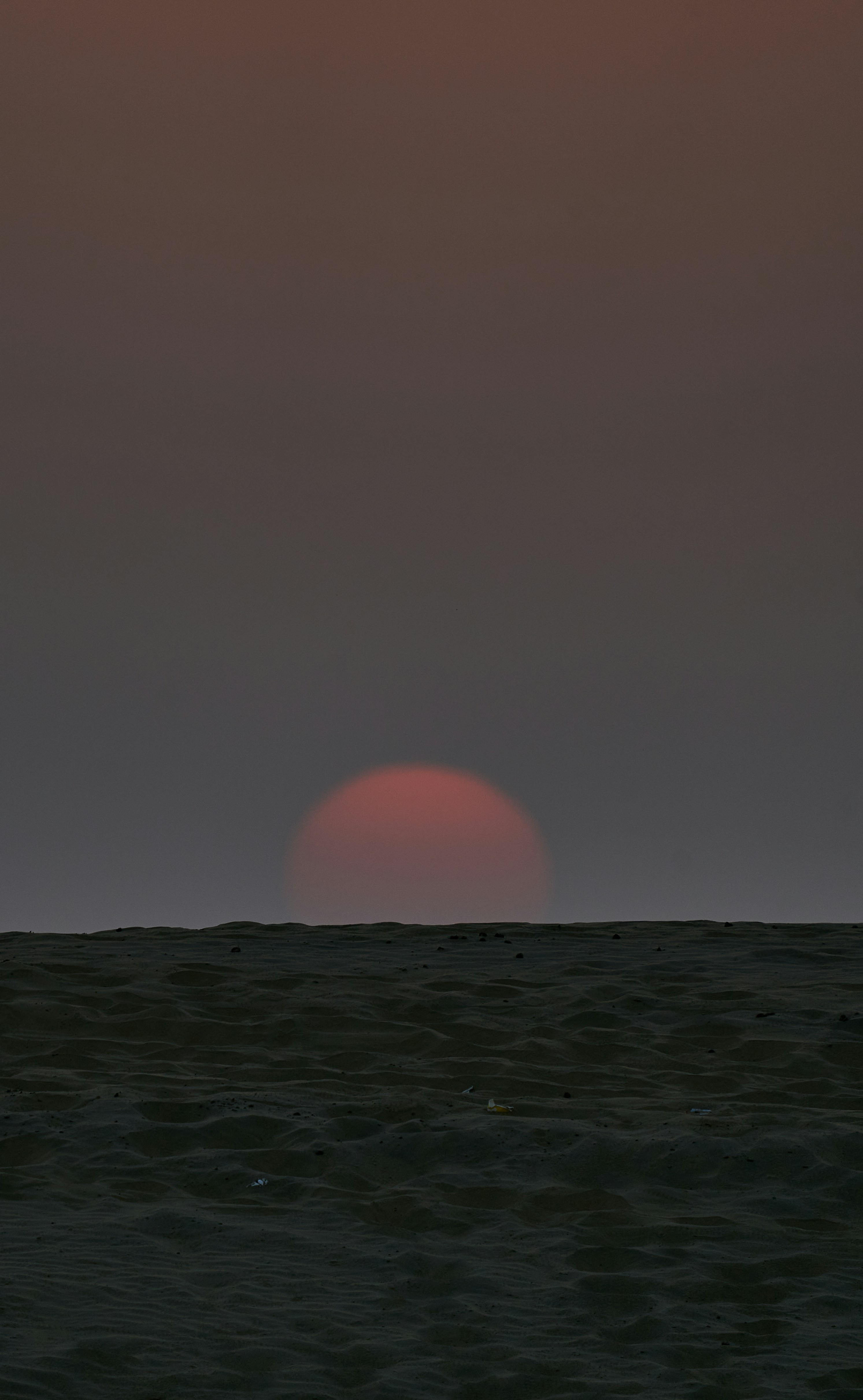 The sun is setting over the horizon of the ocean