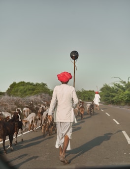 A man walking down the road with a stick in his hand