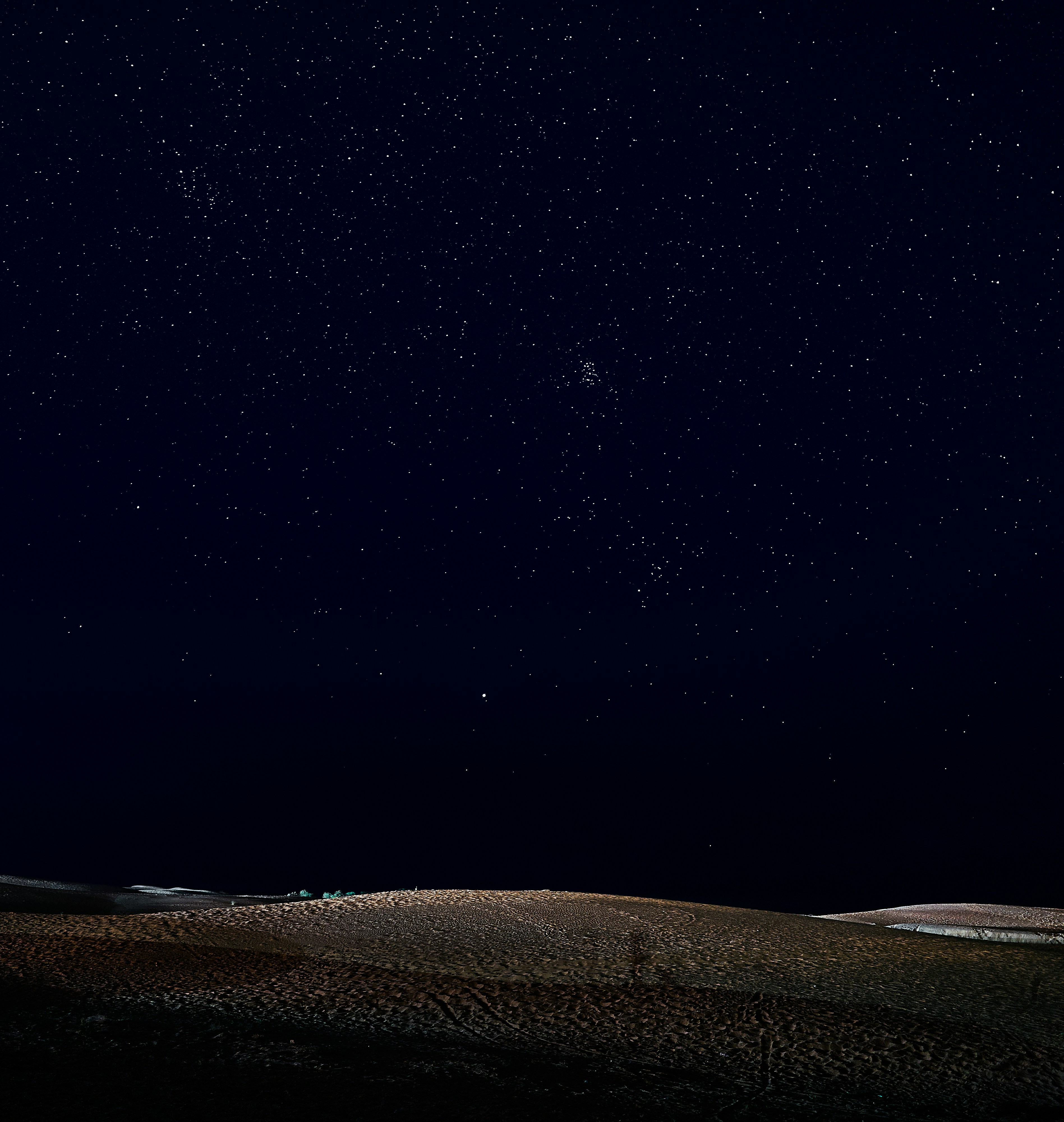 The night sky is full of stars above a hill