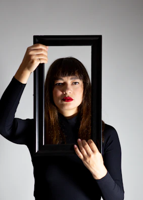 A woman holding a picture frame with her face in it