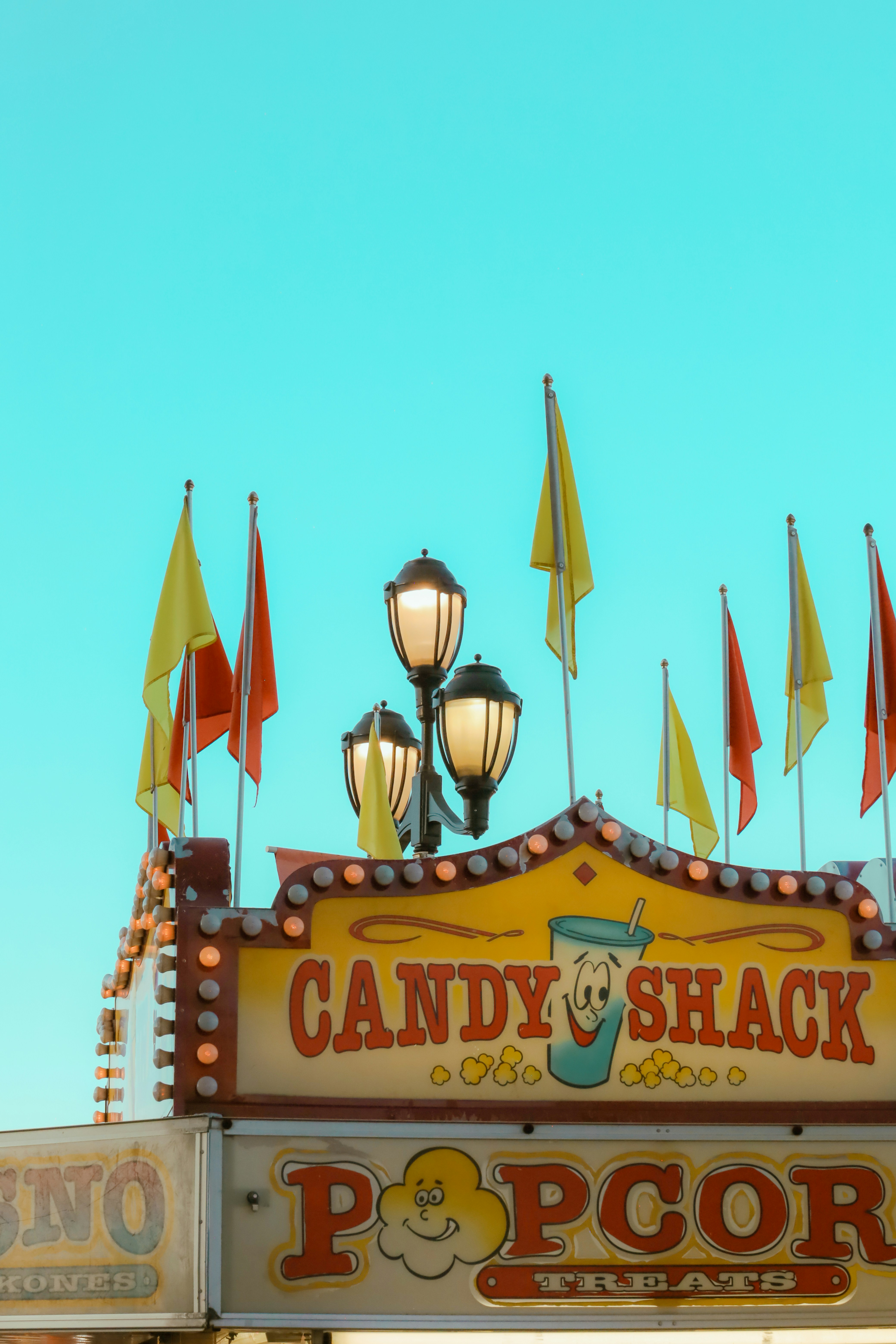 A carnival sign with flags on top of it