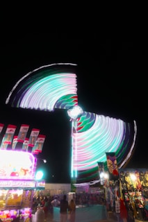 A carnival at night with a ferris wheel in the background