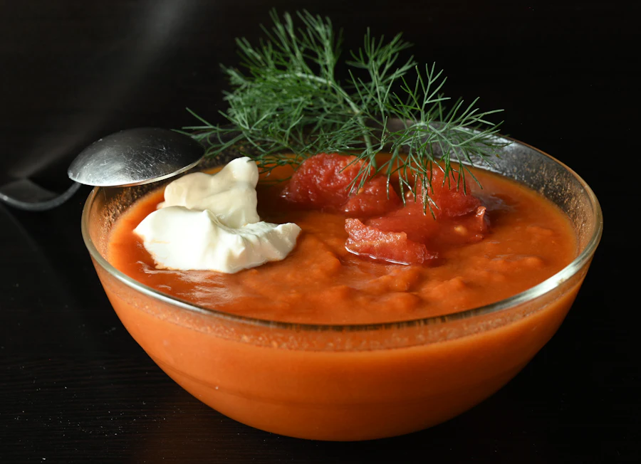 A bowl of creamy salmon soup topped with fresh dill and a spoon of sour cream