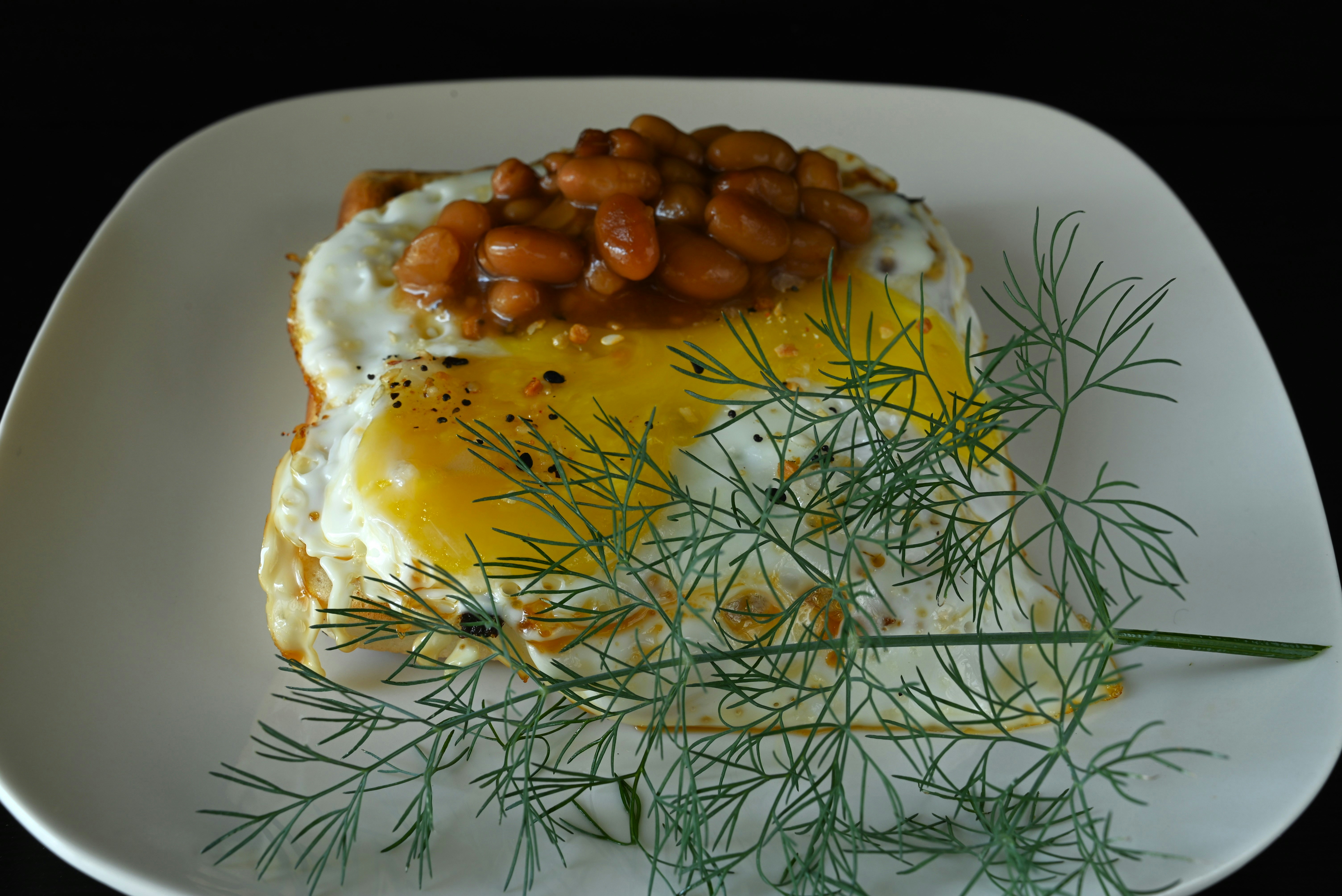 A white plate topped with a baked potato covered in beans