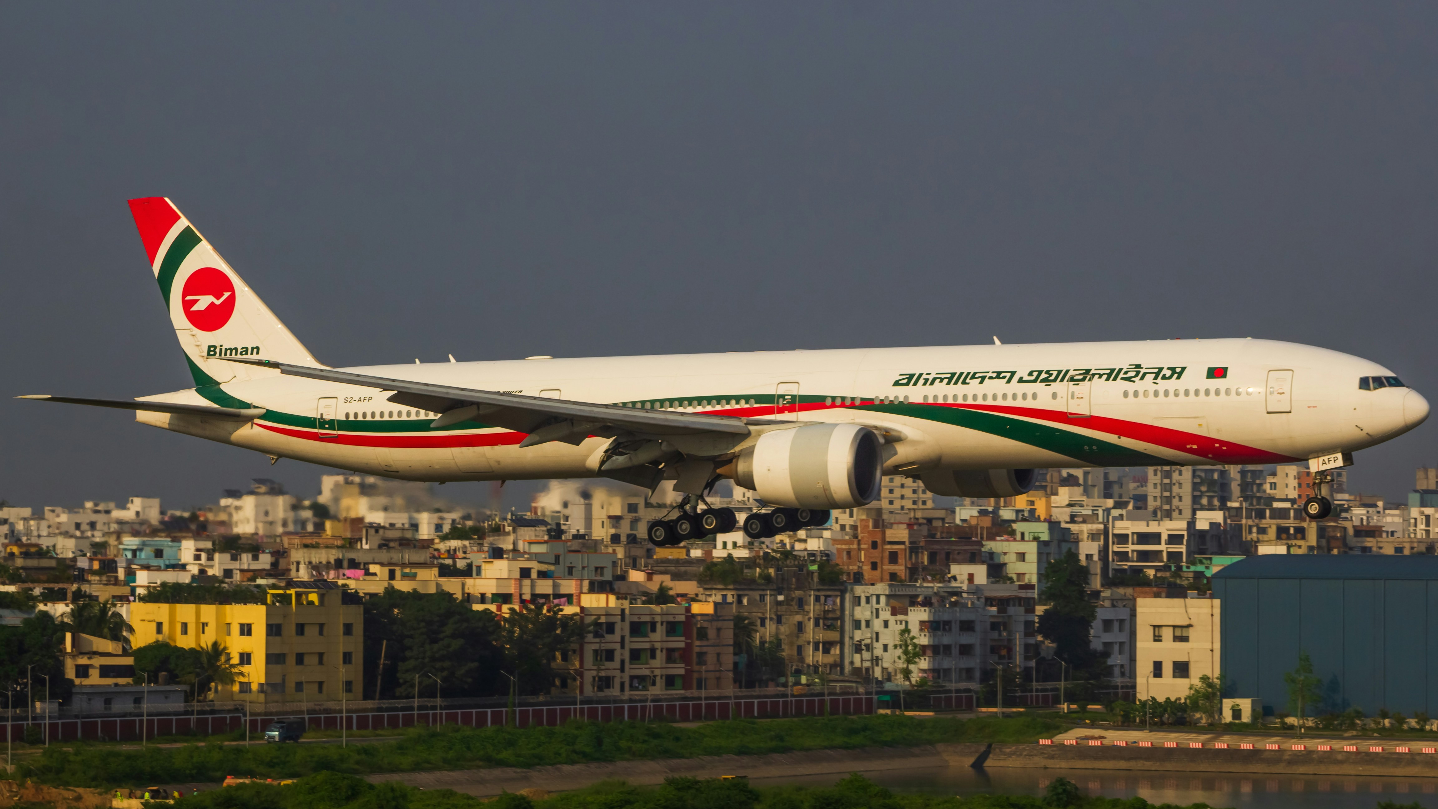A large passenger jet flying over a city, S2-AFP | Biman Bangladesh Airlines | VGHS