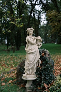 A statue of a woman holding a book in a park