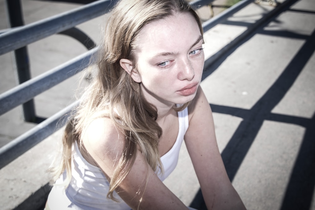 A woman sitting on a bench with her hand on her chin