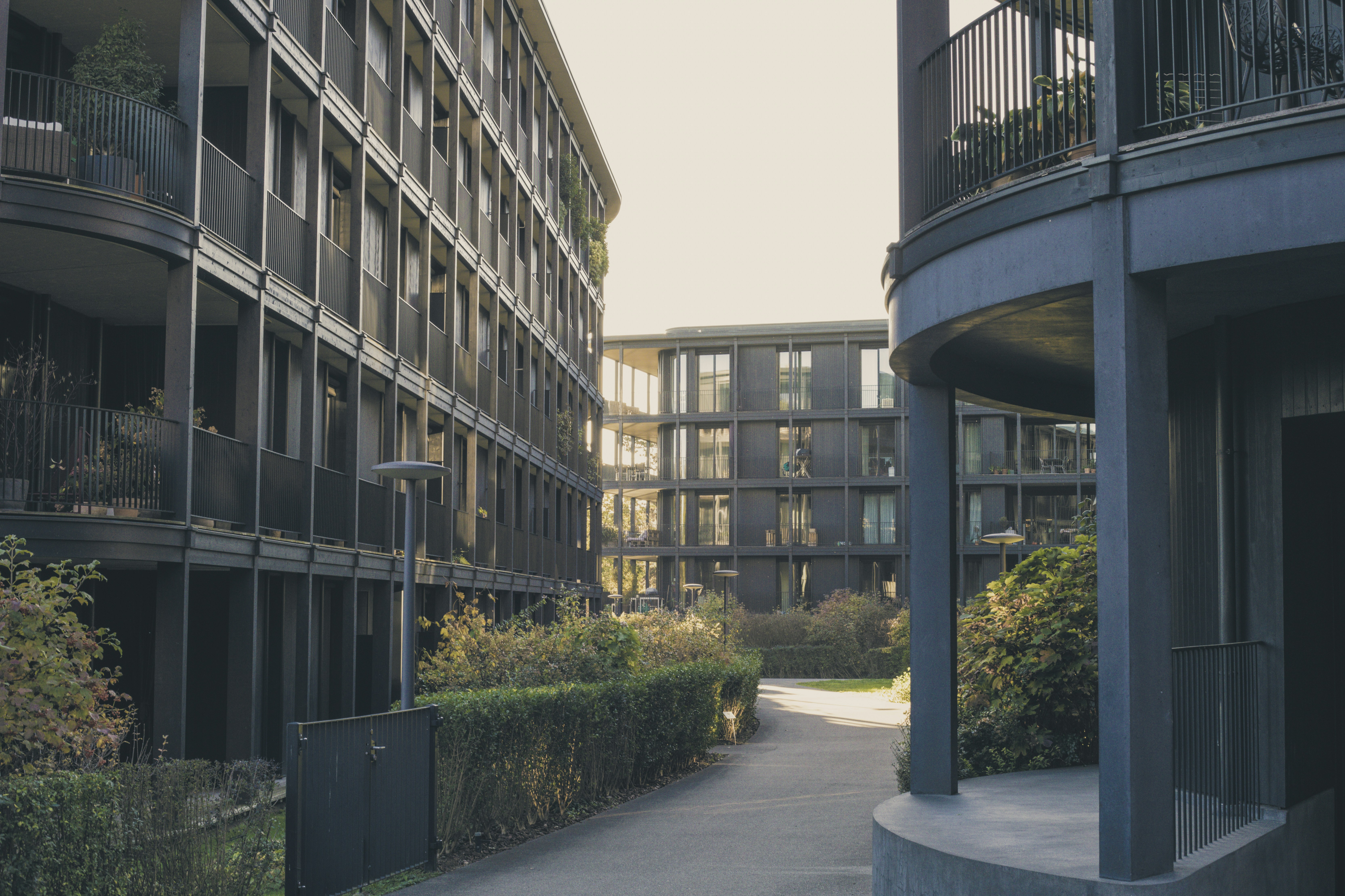 Modern residential apartment complex with green landscaping and well-lit pathways in daylight