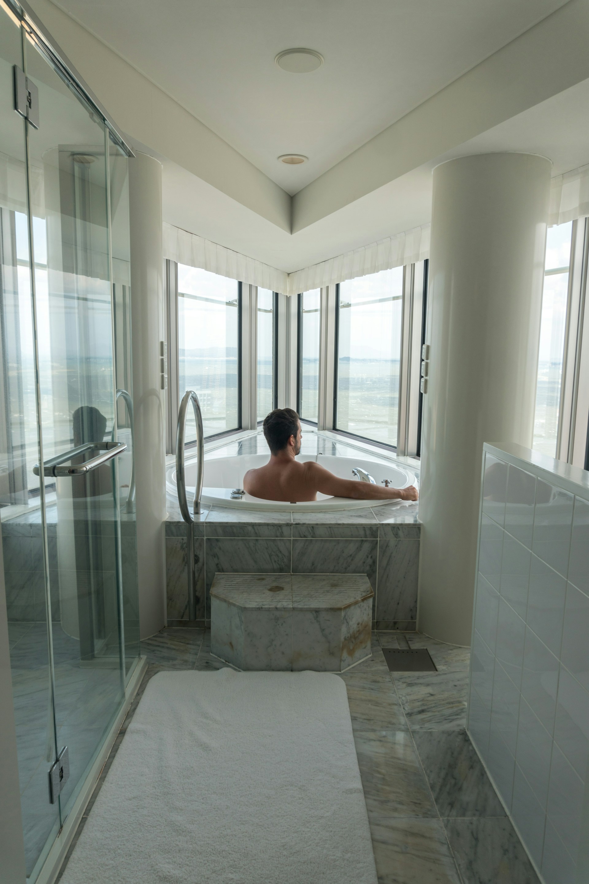 A man in a bathtub with a towel on the floor