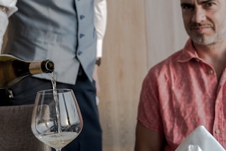 A man pouring a glass of wine at a table