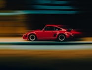 A red car driving down a street at night