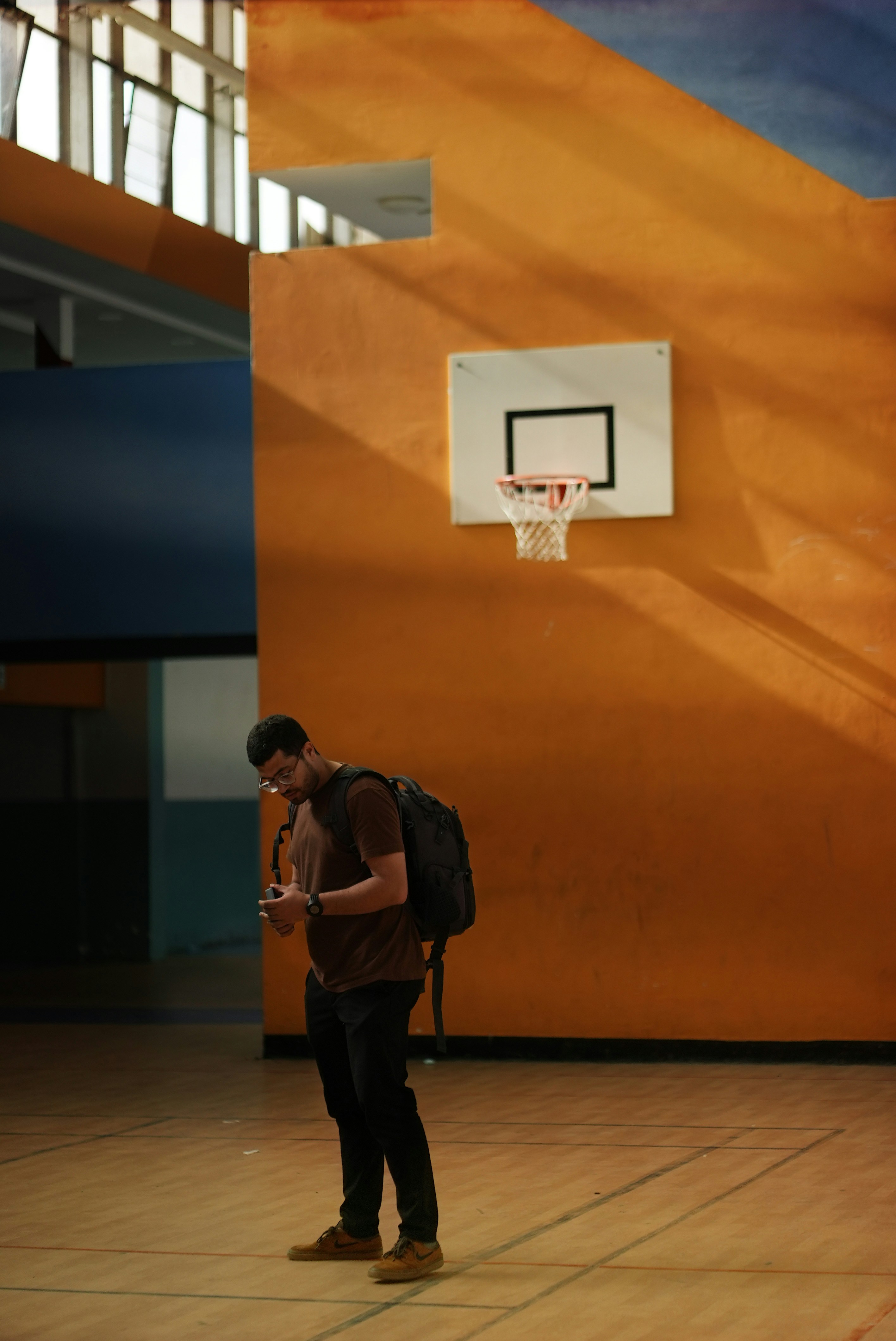 A man standing on a basketball court holding a cell phone