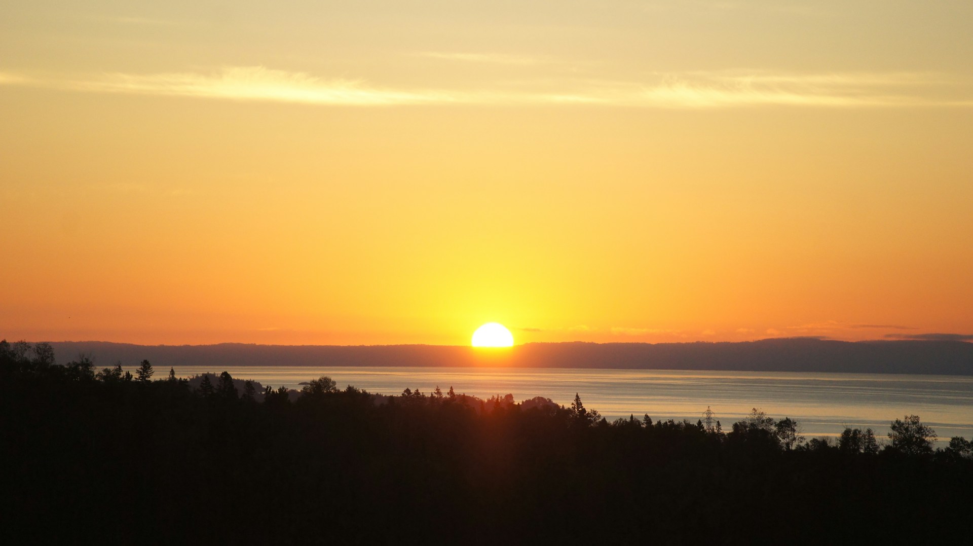 The sun is setting over the horizon of a body of water