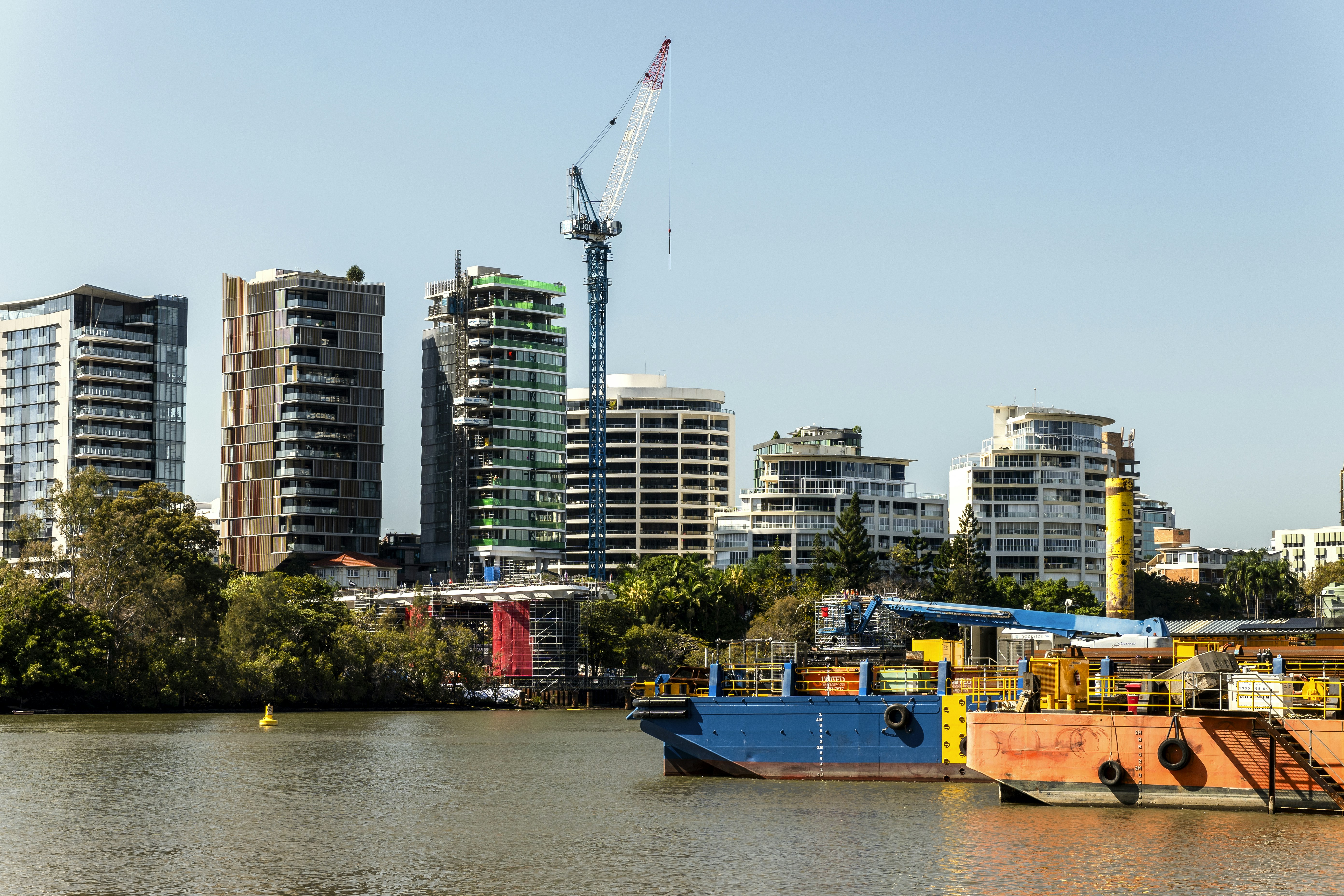 A boat floating on top of a river next to tall buildings