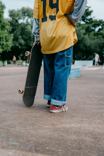 A man holding a skateboard while standing in a parking lot
