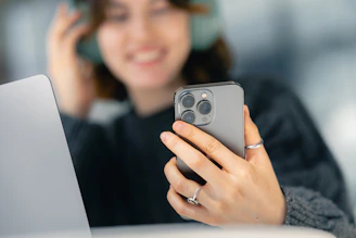 A woman looking at her cell phone while sitting at a table