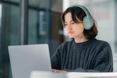 A woman sitting at a table with a laptop wearing headphones