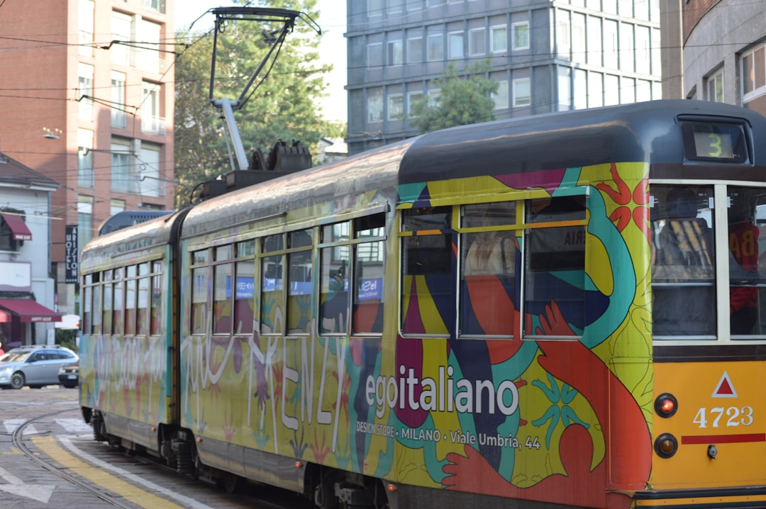 A colorful trolly on a city street with buildings in the background