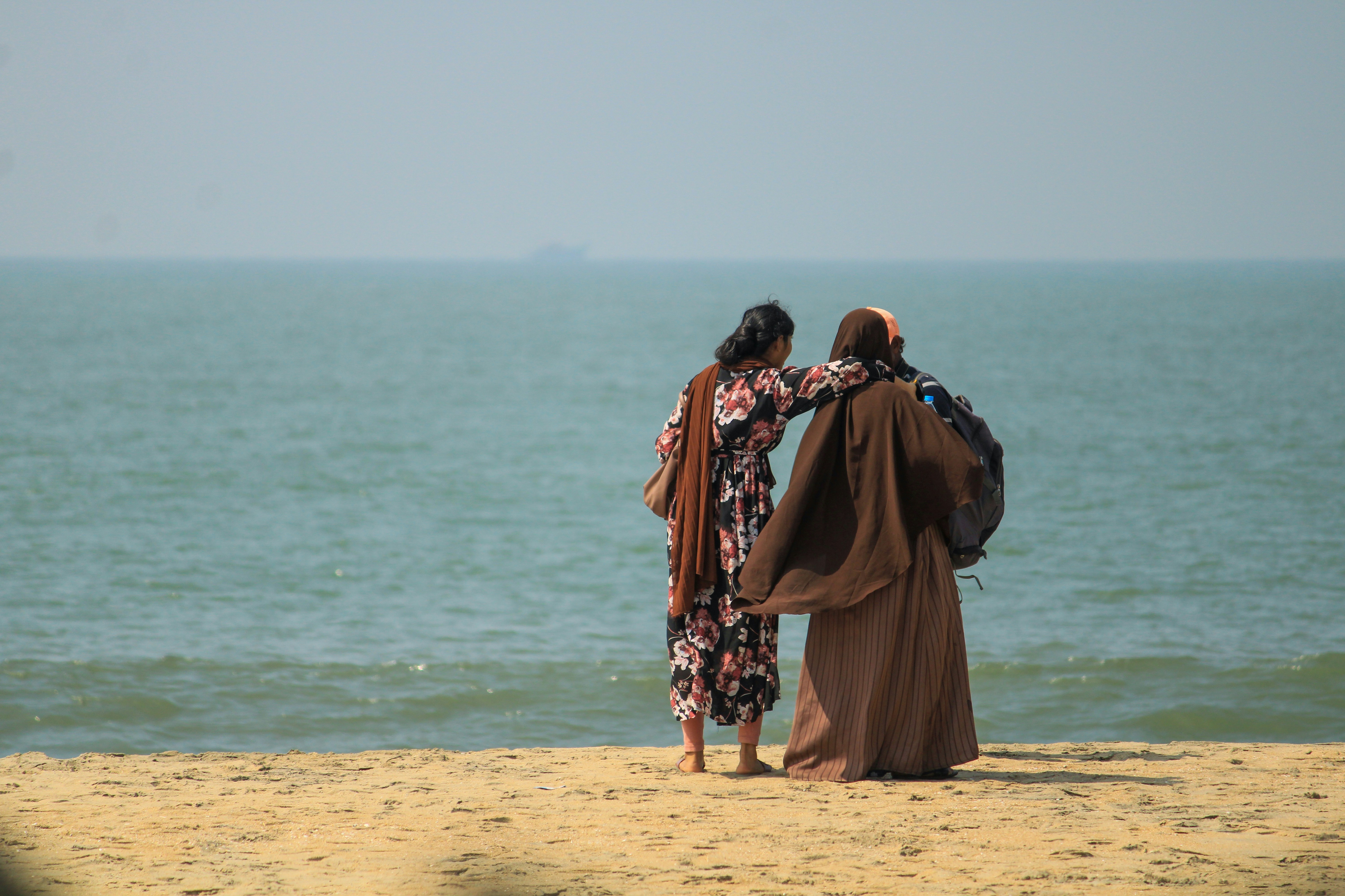 A couple of women standing on top of a sandy beach