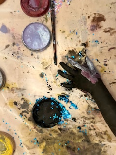 A person painting on a table with paint and brushes