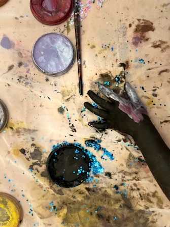 A person painting on a table with paint and brushes