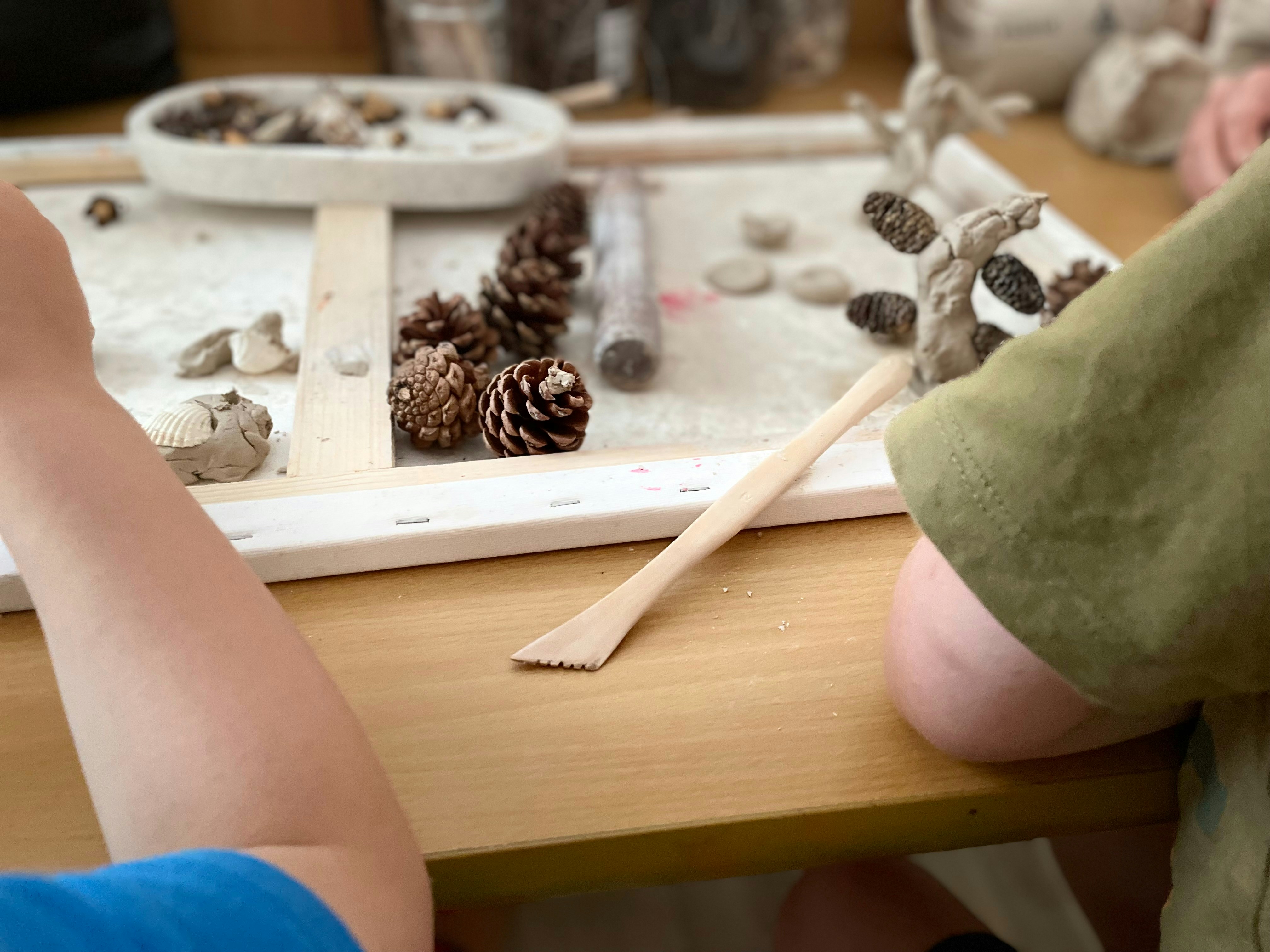 Children creating art outdoors in natural setting with leaves and paint