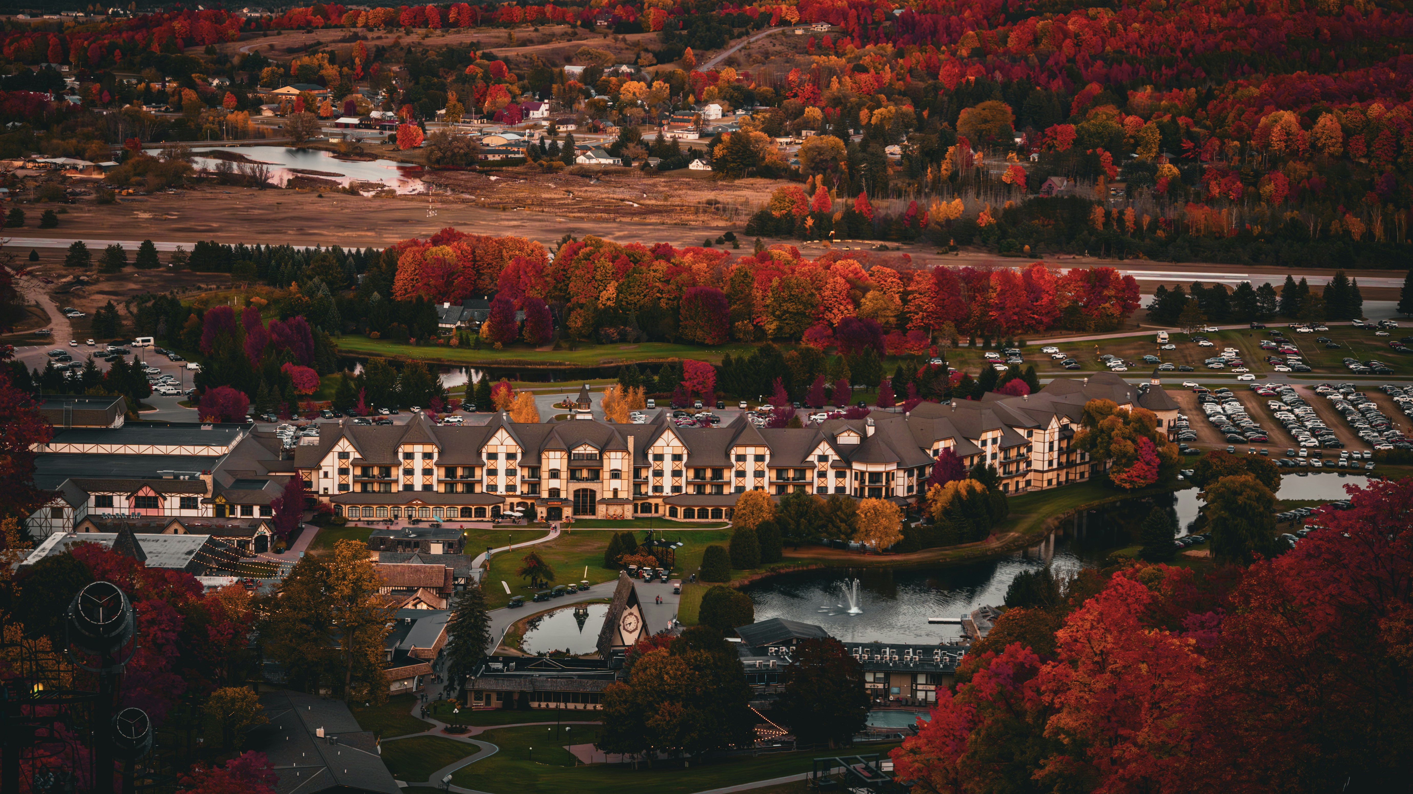 An aerial view of a town surrounded by trees, An amazing vista view of a castle surrounded with fall colors