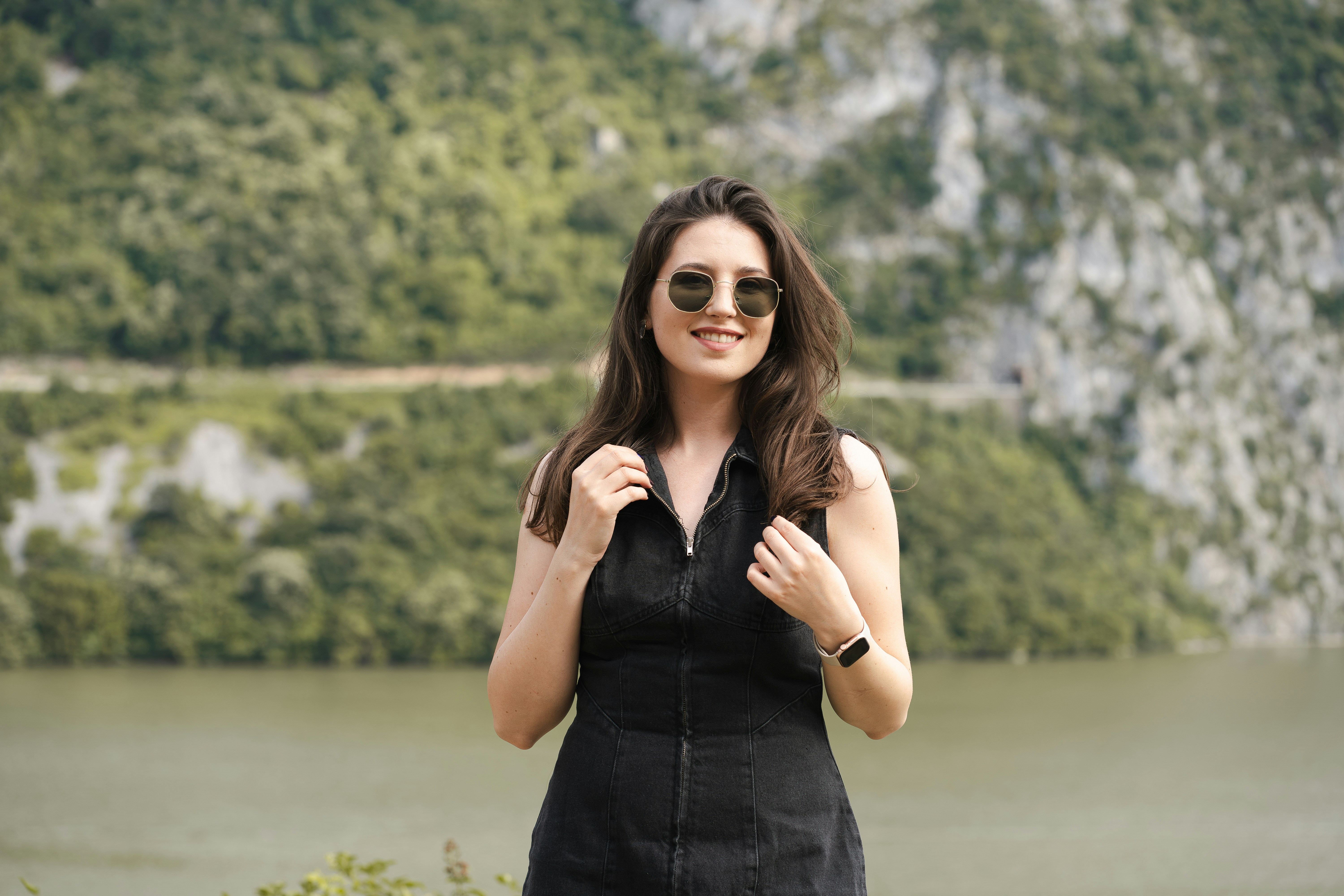 A woman in a black dress standing in front of a lake