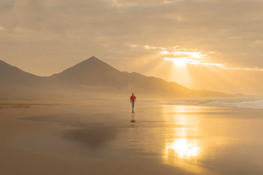 A person walking on a beach at sunset