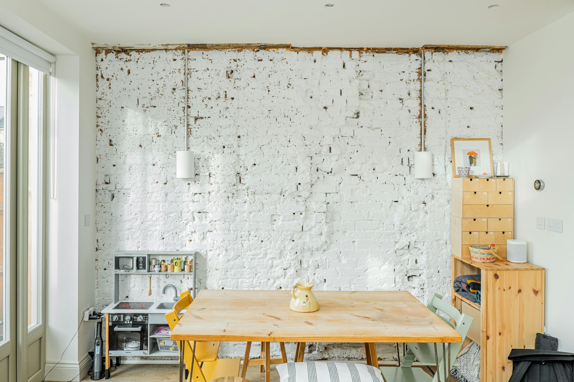 A room with a wooden table and a white brick wall
