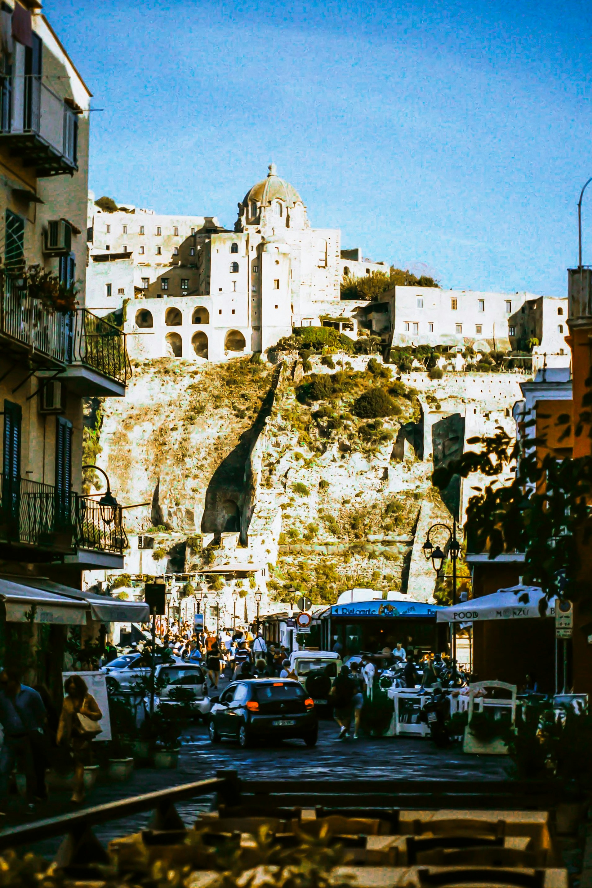 A group of people walking down a street next to tall buildings