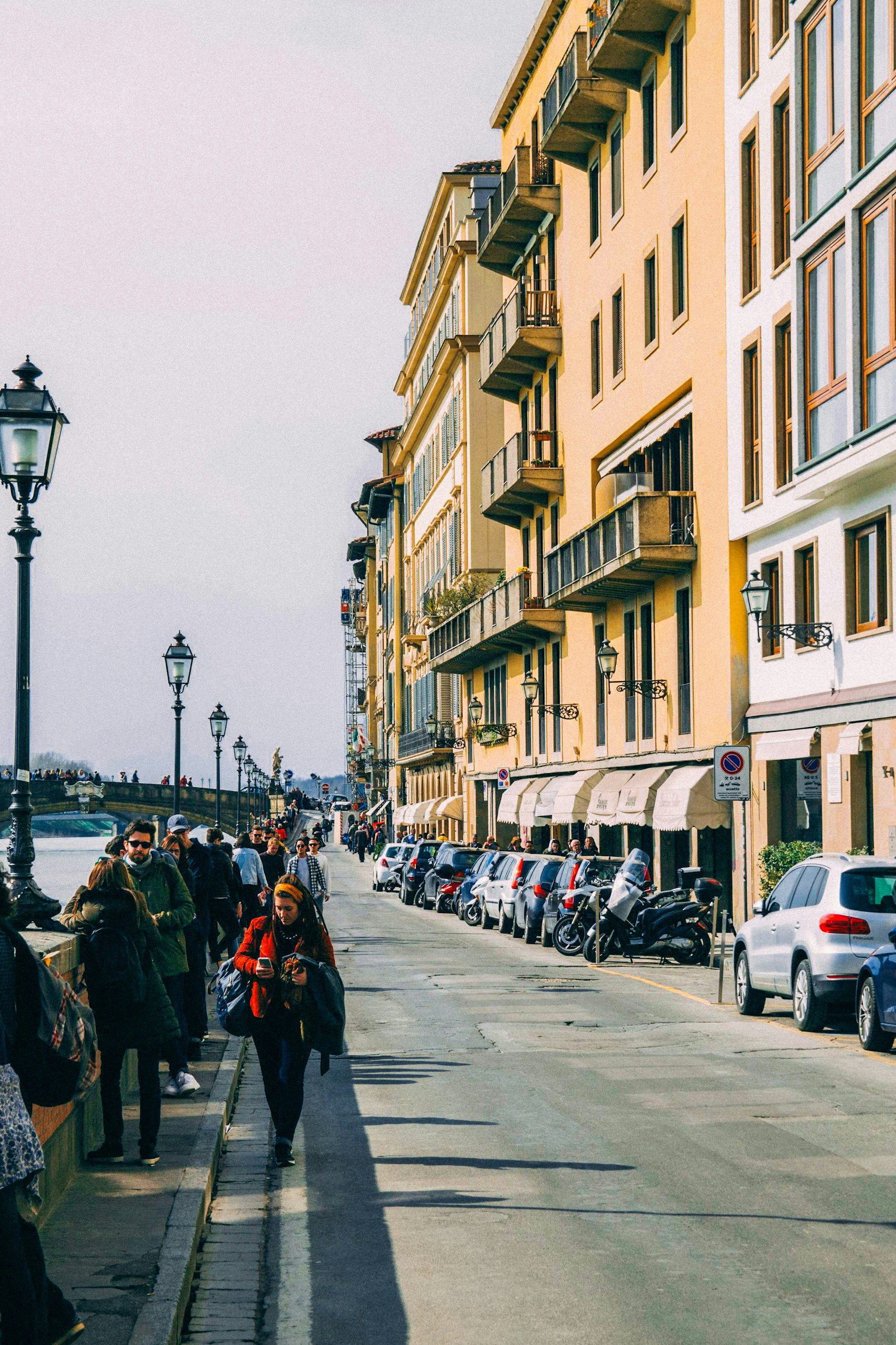 A group of people walking down a street next to tall buildings