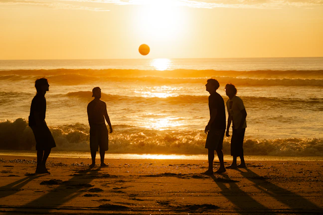 A group of people standing on top of a beach next to the ocean