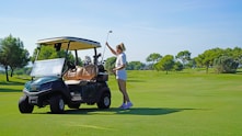 A woman standing next to a golf cart on a golf course