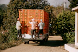 A group of people unloading a large box on the back of a truck