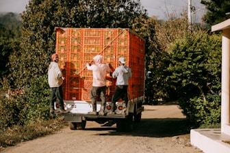 A group of people unloading a large box on the back of a truck