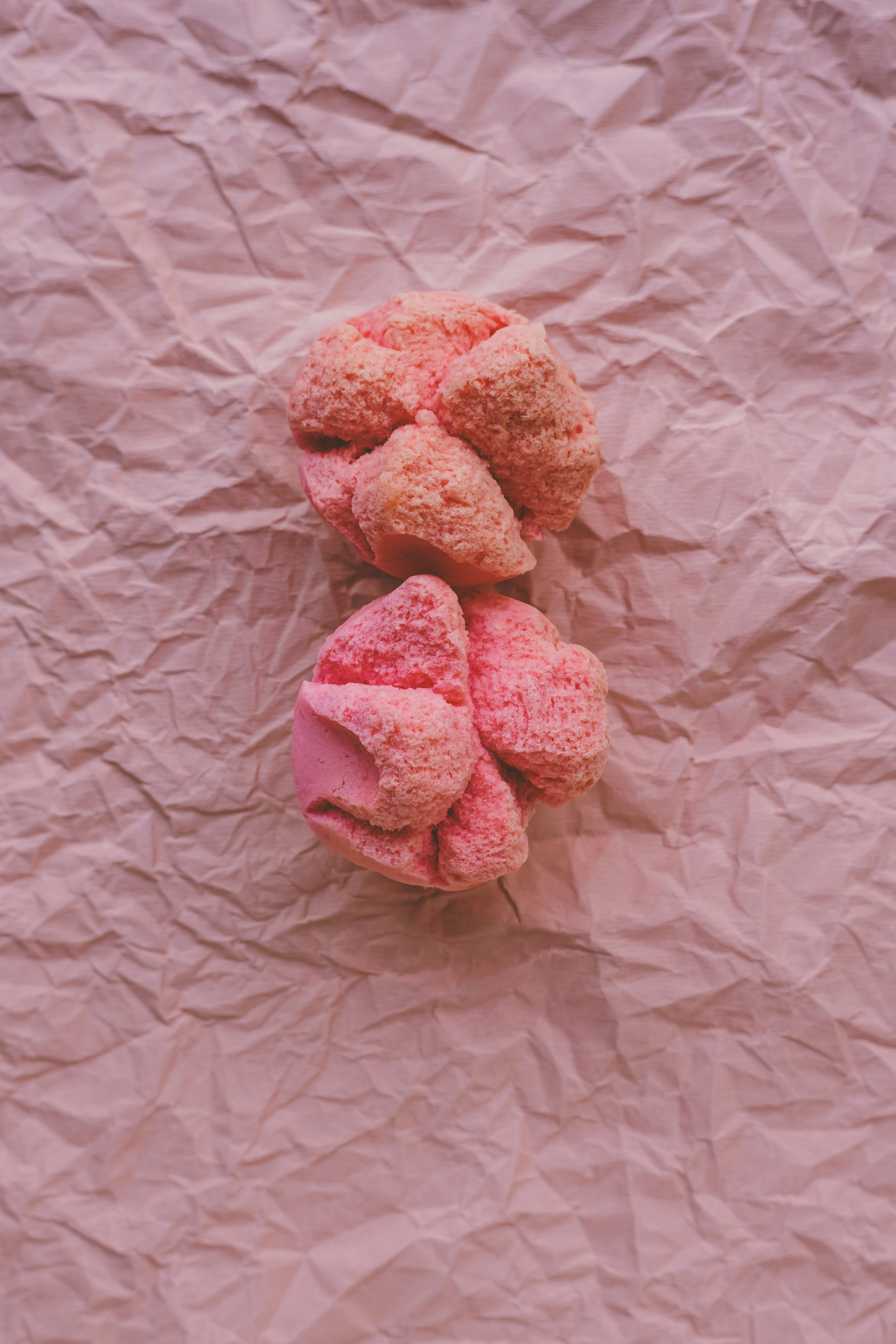 A pile of pink donuts sitting on top of a piece of paper
