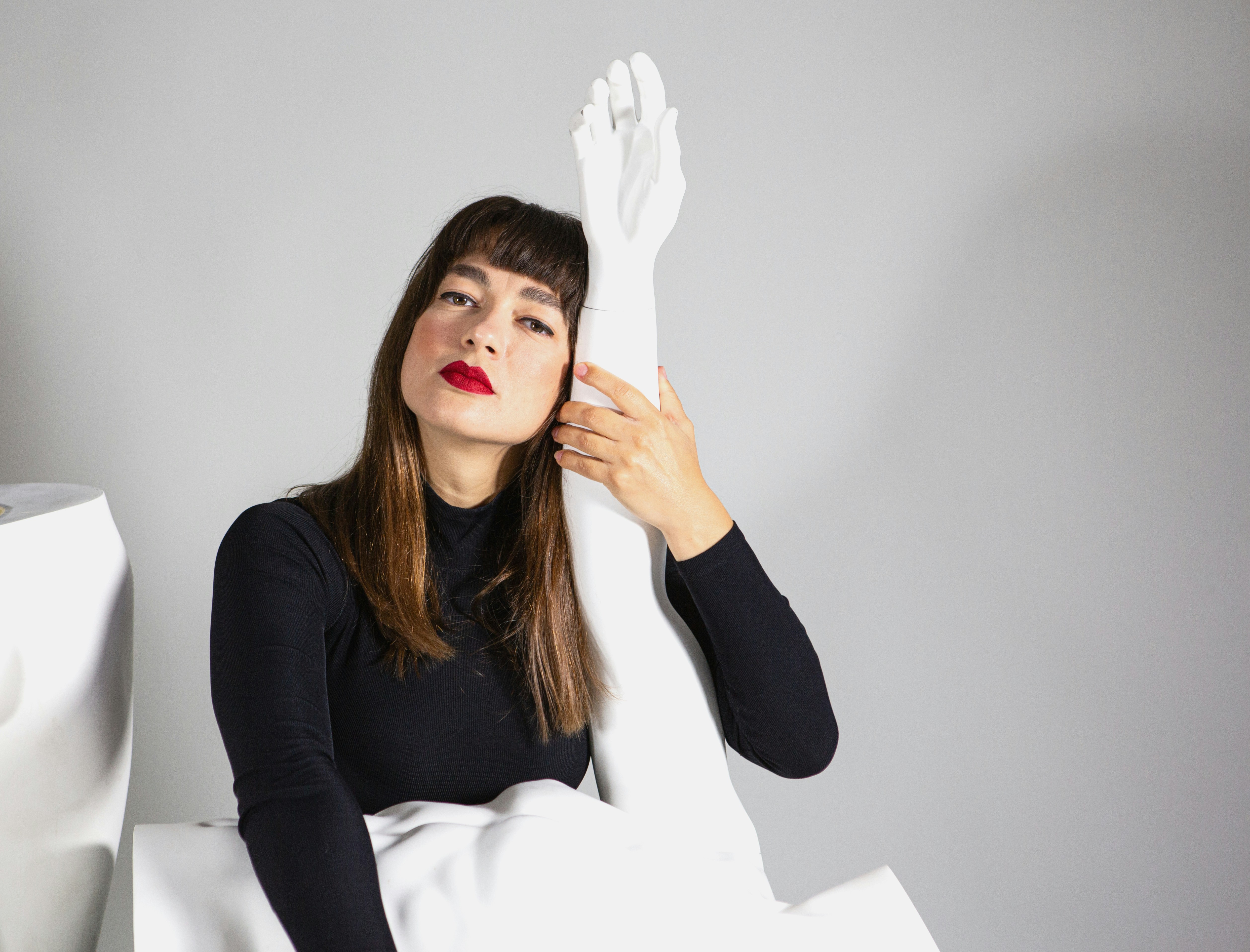 A woman sitting on a bed with a white sheet covering her face